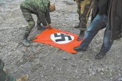 Ополченцы топчут ногами флаг с человеконенавистнической нацистской символикой, найденный на позициях, оставленных батальоном «Азов». фото автора           
			 
